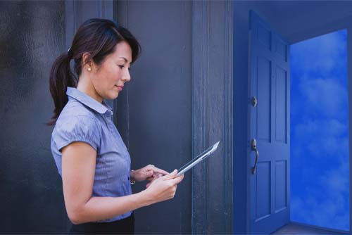 woman on laptop in front of doorway open to clouds